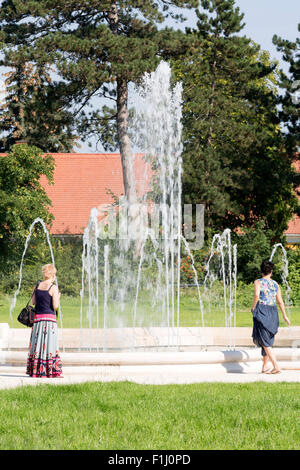 Zwei Damen, die Brunnen und Gartenanlage am Schloss Festetics in Keszthely am Balaton, Grafschaft Zala, Ungarn anzeigen Stockfoto
