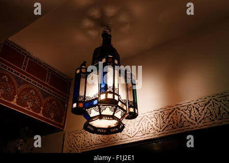 Traditionelle marokkanische afrikanischen Lampe Schatten Lampenschirm Übergabe in Marrakesch Zimmer mit gestalteten Wand beleuchtet beleuchtete Nacht Stockfoto