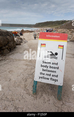 Melden Sie sich am Strand, die Leitung der Öffentlichkeit schwimmen zwischen den roten und gelben Flaggen, Sennen Cove, Cornwall UK Stockfoto