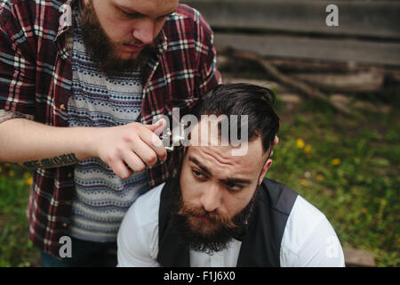 Barbier rasiert ein bärtigen Mannes Stockfoto
