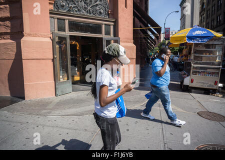 Ein Fußgänger prüft ihr Smartphone am Broadway in New York auf Freitag, 28. August 2015. (© Richard B. Levine) Stockfoto