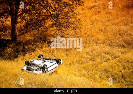 Rollover Compact Car Crash. Weiße stürzte Auto in der Bergstraße Graben in Kalifornien, USA. Verkehrsunfall. Stockfoto
