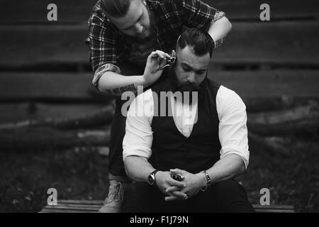 Barbier rasiert ein bärtigen Mannes Stockfoto