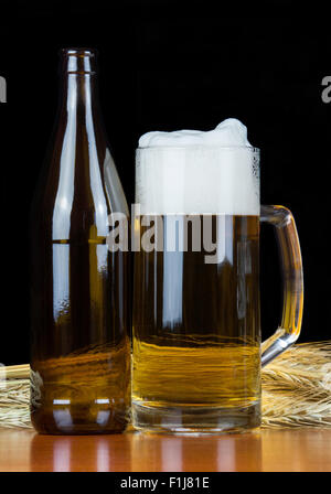 Pint Bier und eine Flasche mit Weizen auf schwarzem Hintergrund. Stockfoto