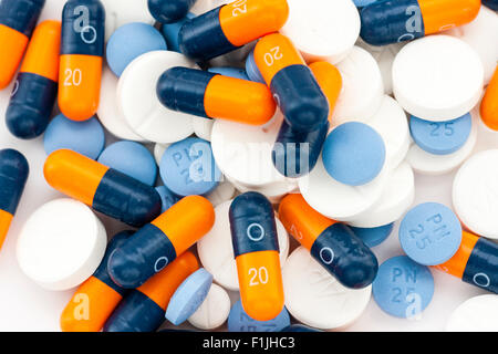 Medizinische Drogen. Stapel von Orange und Blau Kapseln mit blauen und weißen Tabletten auf weißem Hintergrund. Stockfoto