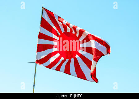 Japanischer Flagge im Wind flattern. Weltkrieg zwei Version, Rising Sun, Jyurokujo Kyokujitsu-ki, gegen den blauen Himmel Hintergrund. Stockfoto