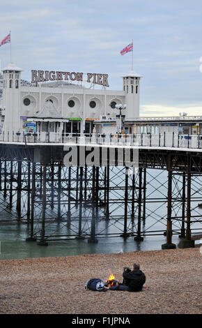 Brighton, UK. 3. September 2015. Ein Mann schlafen rau auf Brighton Beach hält warm neben einem Feuer am frühen Morgen Credit: Simon Dack/Alamy Live News Stockfoto