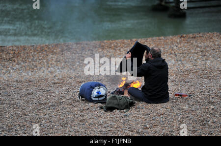 Brighton, UK. 3. September 2015. Ein Mann schlafen rau auf Brighton Beach hält warm neben einem Feuer am frühen Morgen Credit: Simon Dack/Alamy Live News Stockfoto