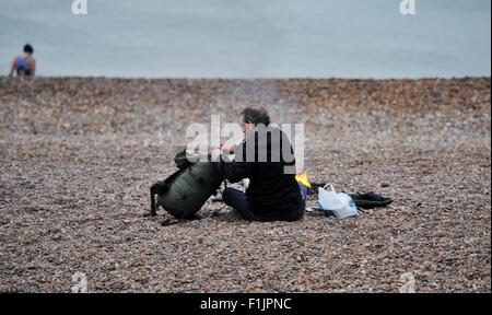 Brighton, UK. 3. September 2015. Ein Mann schlafen rau auf Brighton Beach hält warm neben einem Feuer am frühen Morgen Credit: Simon Dack/Alamy Live News Stockfoto