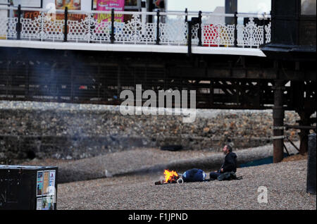 Brighton, UK. 3. September 2015. Ein Mann schlafen rau auf Brighton Beach hält warm neben einem Feuer am frühen Morgen Credit: Simon Dack/Alamy Live News Stockfoto