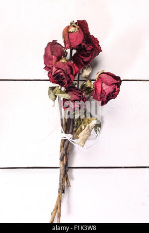 rot getrocknet rose Bouquet wird mit einem Seil gefesselt. Isoliert auf weißem Hintergrund aus Holz Stockfoto