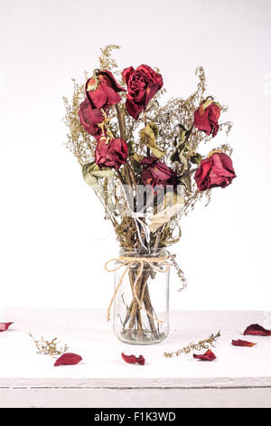 Bouquet von roten getrockneten Rosen in Glasvase auf weißem Hintergrund Stockfoto