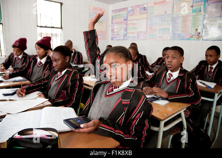 Ecke Schuss eine weibliche High-School-Schüler heben ihre Hand mit den anderen Studenten sitzen im Hintergrund Stockfoto