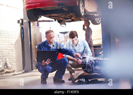 Mechaniker und Kunden mit Laptop prüfenden Motor in Auto-Werkstatt Stockfoto