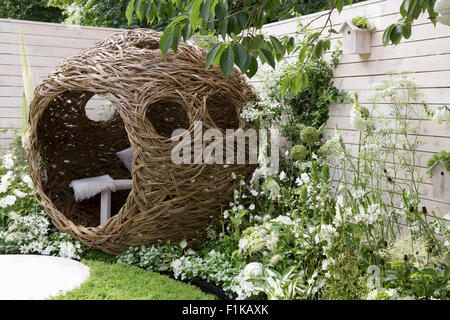 Eine kleine städtische Tierwelt Vogel freundlich Garten Kamille Rasen Schritt Steine und eine gewebte Weidenschote mit Bank und Kissen - weiße Blumen Sommer UK Stockfoto