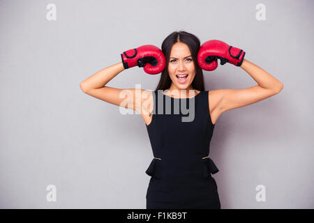 Porträt von eine schöne Geschäftsfrau in Boxhandschuhen auf grauem Hintergrund stehend Stockfoto