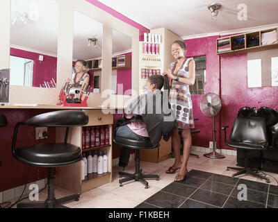 Kunden, die ihr Haar getan im Township Friseursalon, Alexandra, Gauteng, Südafrika Stockfoto