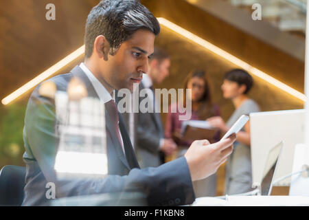 Ernst Kaufmann SMS mit Handy im Büro Stockfoto