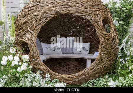 Garten mit moderner Terrasse gewebte Weidenstruktur Bank Vogel Kissen Grenze mit weißen blühenden Blumen Pflanzen gemalt weißen Zaun UK gepflanzt Stockfoto