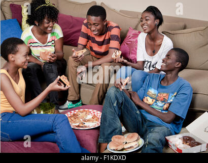 Eine Gruppe von afrikanischen Jugendlichen sitzen zusammen in einer Lounge Essen Stockfoto
