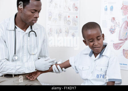 Arzt, einem afrikanische Kind eine Injektion in ein Arztzimmer Stockfoto