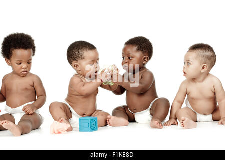 Vier Kinder sitzen vor einem weißen Hintergrund, spielen mit Spielzeug Stockfoto
