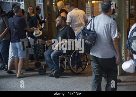 Mann im Rollstuhl auf der Suche nach Liebe von Pendlern nach Hause von Arbeit & Touristen am Eingang zum Grand Central Terminal in New York City. Stockfoto