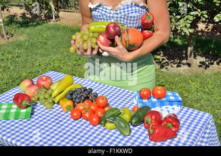 Dame im Garten, gekleidet im Cottage-Stil, mit verschiedenen Arten von Obst und Gemüse. Foto symbolisiert Fruchtbarkeit Stockfoto