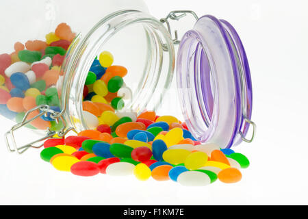 Bunte Jellybean Bonbons aus dem Glas auf weißem Hintergrund Stockfoto