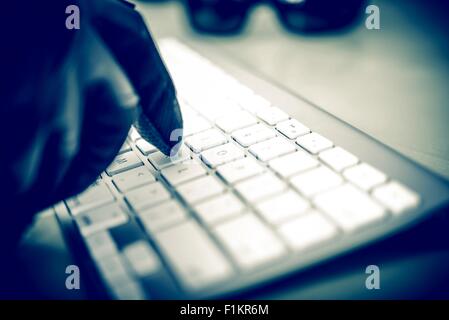 Hacker in Arbeit. Hacker Hand in schwarzen Handschuh Tippen auf der Tastatur. Nahaufnahme Foto Concept. Stockfoto