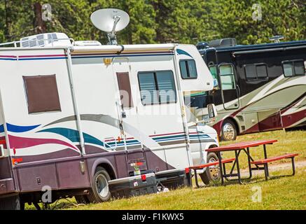 RV Wohnmobile Camping. Freizeitfahrzeuge auf dem Zeltplatz. Klasse C und Klasse A Diesel Wohnmobil im Hintergrund. Stockfoto