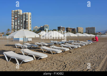 Paar, Sonnenliegen und Apartments in Playa San Juan, am frühen Morgen im späten August, Alicante, Spanien. Stockfoto