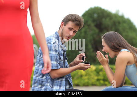 Betrüger Mann betrug während einen Heiratsantrag mit seiner unschuldigen Freundin Stockfoto
