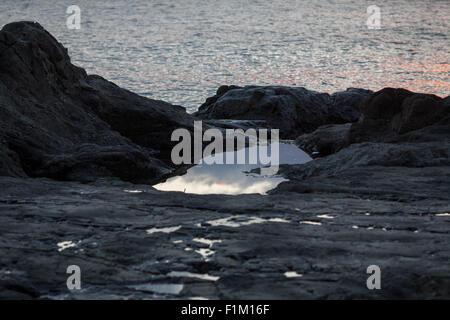 Ursuppe auf dunklen Felsen Ozean Stockfoto