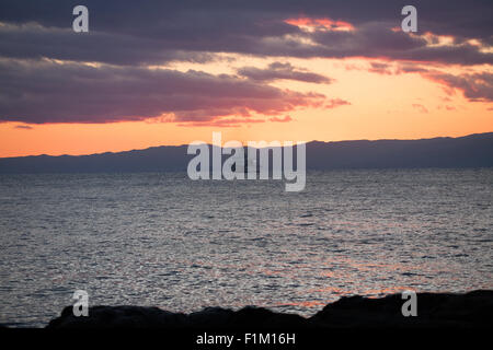 Japanische Küstenwache, auf hoher See mit Bergkette hinter Wolken und Sonnenuntergang Stockfoto
