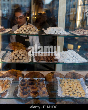 Sachbearbeiterin Confeitaria Nacional Konditorei auf der Praca da Figueira im Zentrum von Lissabon wählt Gebäck aus Schaufenster. Stockfoto