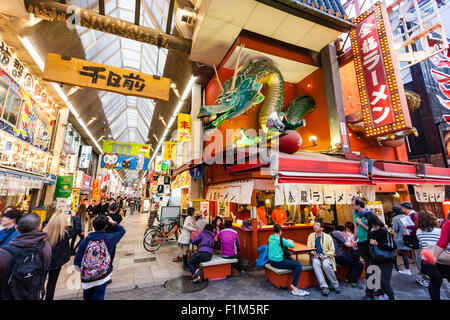 Japan, Osaka. Dotonbori, berühmten Kinryu Ramen noodle Ecke Restaurant mit Golden Dragon Abbildung Zeichen über. Die Leute draußen sitzen Diner essen. Besetzt. Stockfoto