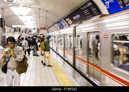 Osaka Shinsaibashi U-Bahn, U-Bahn Station. Passagiere auf Plattform wie der nächste Zug kommt, Bewegungsunschärfe der Zug beschleunigt. Stockfoto