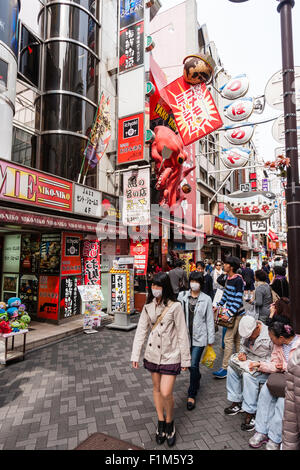 Japan, Osaka. Dotonbori. Menschen außerhalb Takoyaki Restaurant, Dotonbori Kukuru Honten, mit großen roten Oktopus Schild über Fenster entfernt. Stockfoto