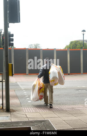 Mann trägt viele Argos Einkaufstaschen im Zentrum der Stadt in Bedford, Bedfordshire, England Stockfoto