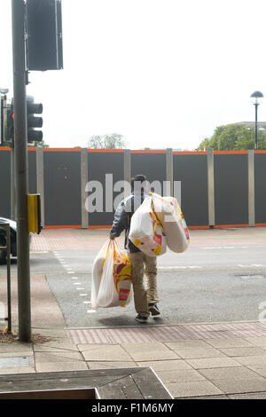 Mann trägt viele Argos Einkaufstaschen im Zentrum der Stadt in Bedford, Bedfordshire, England Stockfoto