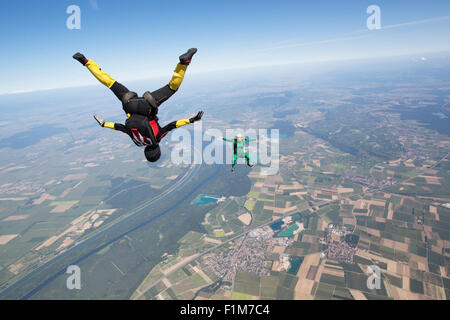 Fallschirmspringer Team trainiert in den blauen Himmel zusammen. Die Frau ist Kopf fliegen und das Männchen in der Sit-Lage von 125 km/h. Stockfoto