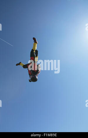 Dieser Fallschirmspringer Mädchen fliegt in einem Kopf nach unten in den blauen Himmel ohne Wolken. Sie ist schnell mit 130 km/h auf dem Kopf fliegen. Stockfoto