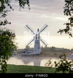 Atemberaubende Landschaft mit Windmühle und Fluss bei Sonnenaufgang am Sommermorgen Stockfoto