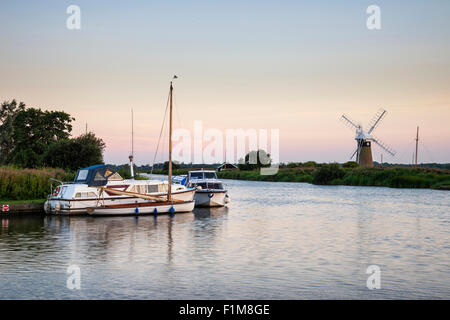 Atemberaubende Landschaft mit Windmühle und Fluss bei Sonnenaufgang am Sommermorgen Stockfoto