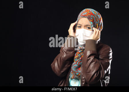 muslimische Frau tragen Einweg Gesichtsmaske auf schwarzem Hintergrund. Stockfoto
