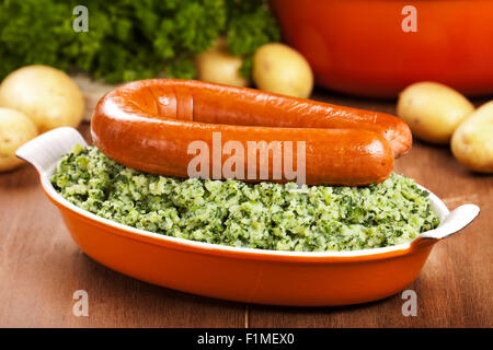 Ein rustikaler Tisch mit ein Gericht mit "trafen sich Boerenkool schlimmsten Fall" oder Grünkohl mit geräucherter Wurst, traditionelle niederländische Gerichte. Stockfoto