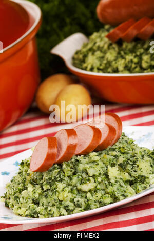 Einem rustikalen Tisch mit einer Platte mit "trafen sich Boerenkool schlimmsten Fall" oder Grünkohl mit geräucherter Wurst, traditionelle niederländische Gerichte. Stockfoto