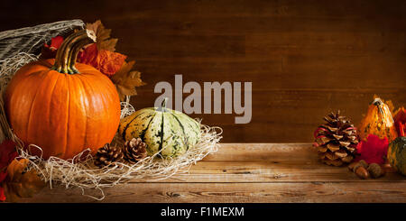 Eine rustikale Herbst Stilleben mit Kürbissen und einem Korb auf einem Holztisch. Stockfoto