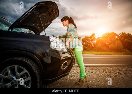 Frau auf der Straße in der Nähe des Autos. Schäden Sie an Fahrzeug-Probleme auf der Straße. Stockfoto